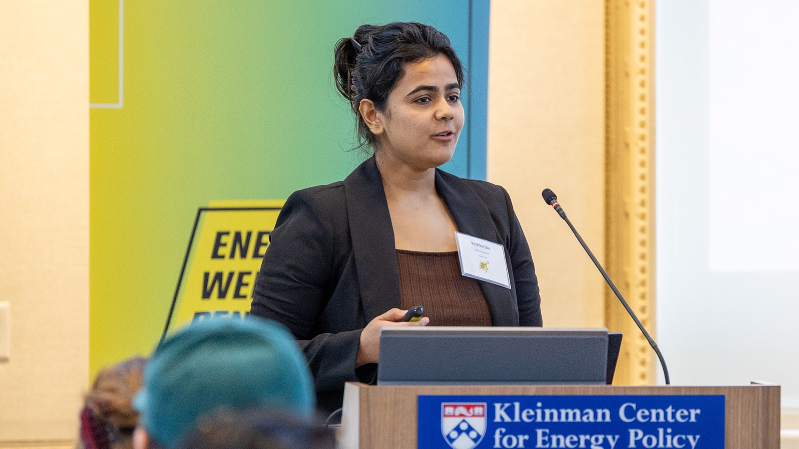 Kritika Jha standing at a podium with a sign that reads Kleinman Center for Energy Policy